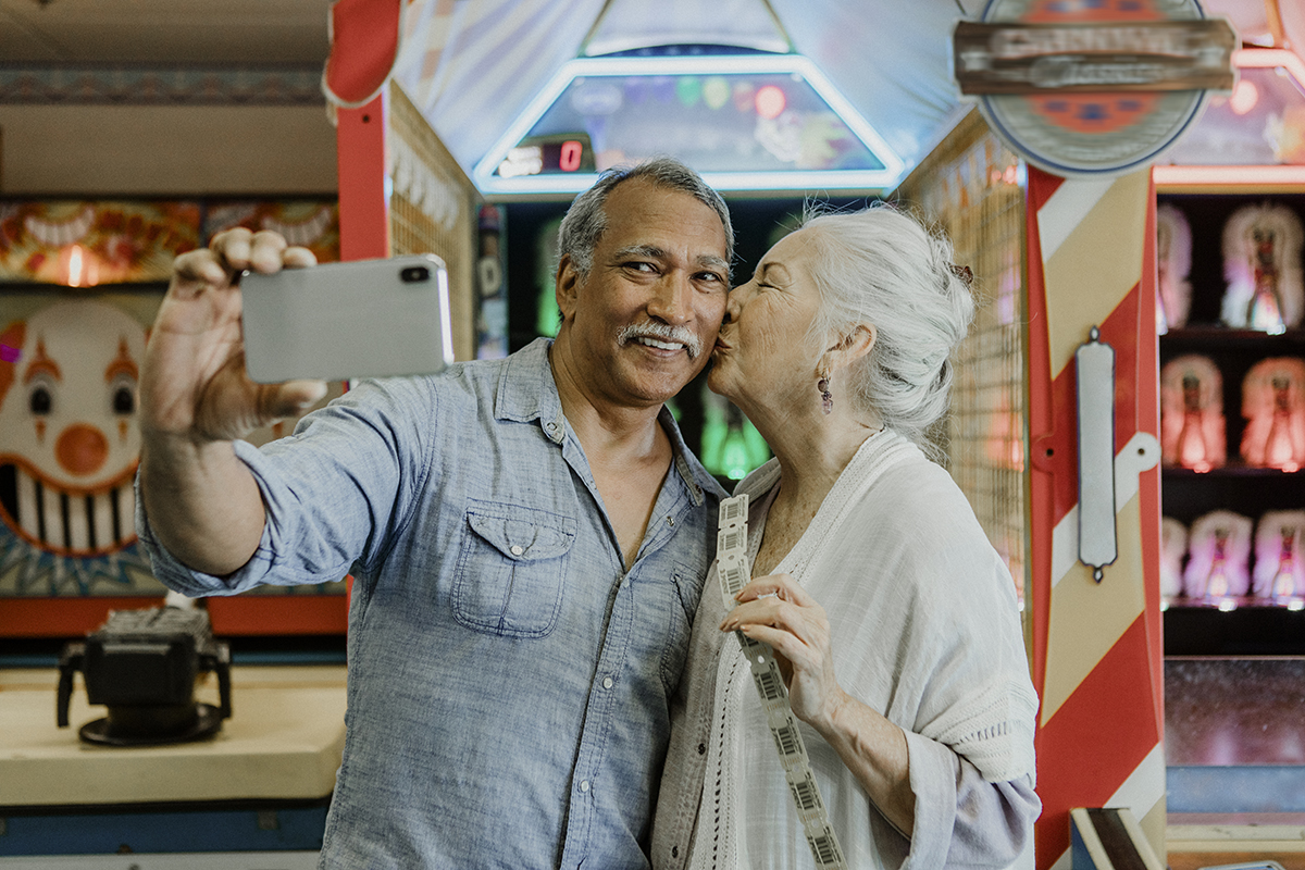 Happy senior couple taking a selfie with raffle tickets